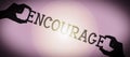 Encourage - human hands holding black silhouette word Royalty Free Stock Photo