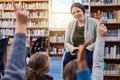 She always encourages class participation. a group of elementary school kids raising their hands to their teacher in the Royalty Free Stock Photo