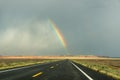 End of a rainbow on a black a road, south west America Royalty Free Stock Photo