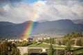 End of a rainbow in the sky over the city in sunny day