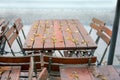 End of season, unused outdoor folding set of wood and metal from a street restaurant in autumn with fallen down seeds and leaves