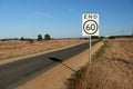 End of speed restriction road sign on a narrow Australian country road signifying an end to a 60 kilometre per hour safety speed l Royalty Free Stock Photo