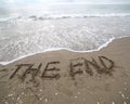 THE END text written on the sand and the wave that is deleting t Royalty Free Stock Photo