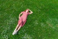 Ender beautiful woman in rose dress lay on a spring grass, sunny meadow, candid people