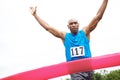 Ending in a win. Cropped front view of a male athlete winning a race with his arms raised. Royalty Free Stock Photo