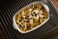 Endives or chicory gratin with apple, ham, cheese and pumpkin seeds in a casserole on a baking grid fresh from the oven