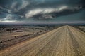 Endless gravel road in monotonous life hostile arid barren surreal gray stone and sand atacama desert landscape, ominous dark Royalty Free Stock Photo