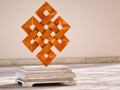 Endless Knot, Buddhist symbol. 3D illustration of the Buddhist symbol - Endless Knot - made of wood on a marble base in a warm lig