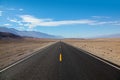 Endless and lonely blacktop road going into the mountain range entering Death Valley National Park Royalty Free Stock Photo