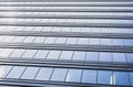 Endless rows of identical gray Windows of a modern glass office building-a skyscraper which reflects the blue sky and white clouds Royalty Free Stock Photo