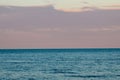 Endless sea at sunset and pink clouds on the horizon