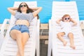 Endless summer! Cute baby and mother relaxing at sunbed