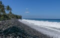 An endless virgin pebble beach with palm trees and tropical vegetation on Bali Island in Indonesia. The waves wash the stony coast Royalty Free Stock Photo