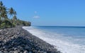 An endless virgin pebble beach with palm trees and tropical vegetation on Bali Island in Indonesia. The waves wash the stony coast Royalty Free Stock Photo