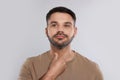 Endocrine system. Man doing thyroid self examination on light grey background Royalty Free Stock Photo