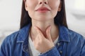 Endocrine system. Woman doing thyroid self examination indoors, closeup