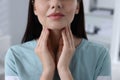 Endocrine system. Woman doing thyroid self examination indoors, closeup