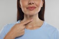 Endocrine system. Woman doing thyroid self examination on light grey background, closeup