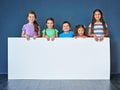 Endorsed by kids for kids. Studio shot of a diverse group of kids standing behind a large blank banner against a blue Royalty Free Stock Photo