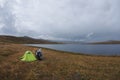 Enduro motorcycle alone traveler near green tent at dark gloom fog steppe shore of lake Royalty Free Stock Photo