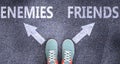 Enemies and friends as different choices in life - pictured as words Enemies, friends on a road to symbolize making decision and