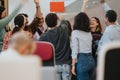 Energetic and cheerful crowd of diverse people raising hands in joyous celebration at a business seminar or team Royalty Free Stock Photo