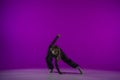 Energetic contemporary dance in purple studio light: young girl in black clothes shows grace and passion for dance. Full