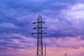 Energetic crisis situation conceptual image, silhouette of electricity pylons and power line cables against dramatic purple sunset