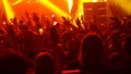 Energetic crowd of people dancing with their hands up at the punk concert - red lighting Royalty Free Stock Photo