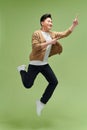 Energetic excited young Asian man jumping and pointing hand to empty space aside Royalty Free Stock Photo