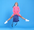 Energetic happy schoolgirl in eyewear with funny surprised facial expression jumping up in air