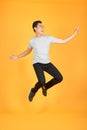 Energetic happy young Asian man in casual clothes jumping, studio shot isolated in orange background Royalty Free Stock Photo