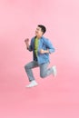 Energetic happy young Asian man jumping isolated in pink background