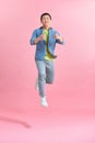 Energetic happy young Asian man jumping isolated in pink background