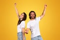 Energetic and happy young couple in white t-shirts and blue jeans joyously dancing