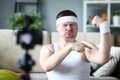 Energetic joyful male blogger measuring bicep size while smiling and updating blog