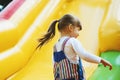 An energetic little girl is playing on a colorful inflatable slide. A child is having fun on an inflatable trampoline. Happy child Royalty Free Stock Photo