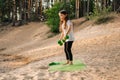 Little lady working out with dumbbells in hands standing on sporty rug outdoor. Junior athlete training on sandy beach. Royalty Free Stock Photo