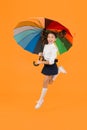 Energetic look. Adorable girl jumping with autumn look on yellow background. Cute little schoolchild having glamour look