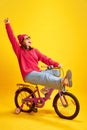 Energetic portrait of girl loudly shouting of joy and happiness because holidays begun riding bicycle against yellow