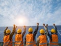 Energetic renewable energy team celebrating at solar panel array under blue sky with sun and reflective modules Royalty Free Stock Photo