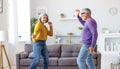 Energetic senior family couple dancing together in living room at home, moving to music Royalty Free Stock Photo