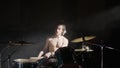 Energetic shirtless male drummer with beard playing drums