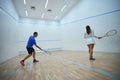 Energetic sportswoman practices refining hitting skills with squash man coach