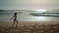 Energetic woman jogging beach at sunrise. Girl spinning on coast feeling happy.