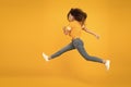 Energetic woman running or jumping. Skinny jeans suits her. Sexy girl yellow background. Sensual girl in casual style