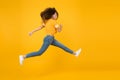 Energetic woman running or jumping. Skinny jeans suits her. Sexy girl yellow background. Sensual girl in casual style