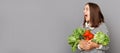 Energize with vitamin-rich vegetable. Surprised woman holding vegetables isolated over gray background, advertisement area, copy
