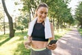 Energize your morning. Cheerful fit woman in sportswear refreshing, drinking water and using her smartphone after