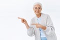 Energized, active happy and healthy senior lady showing gladly great promo, pointing left and bending to express her Royalty Free Stock Photo